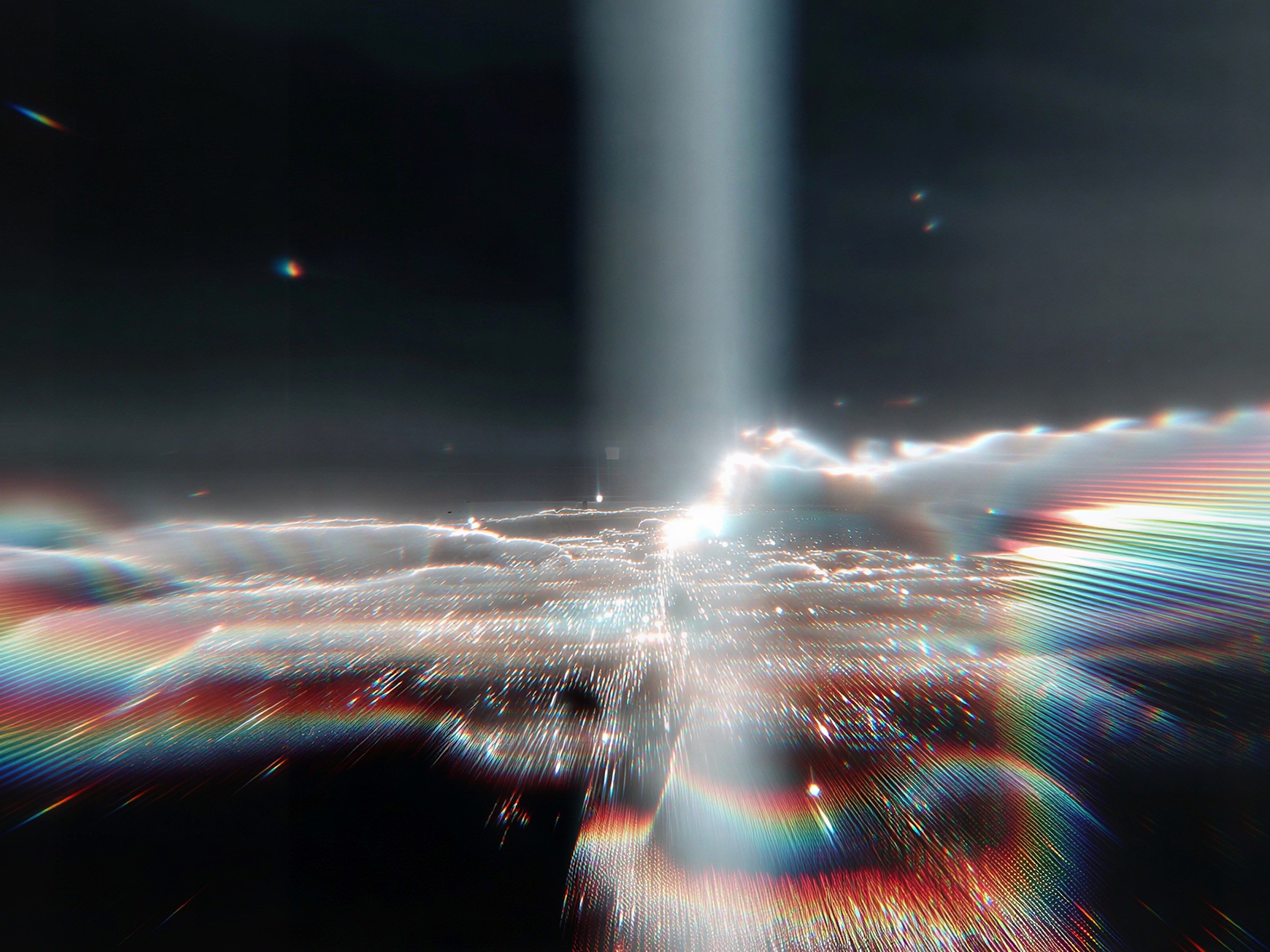 Un faisceau de lumière se divisant en traînées arc-en-ciel dans un espace sombre.