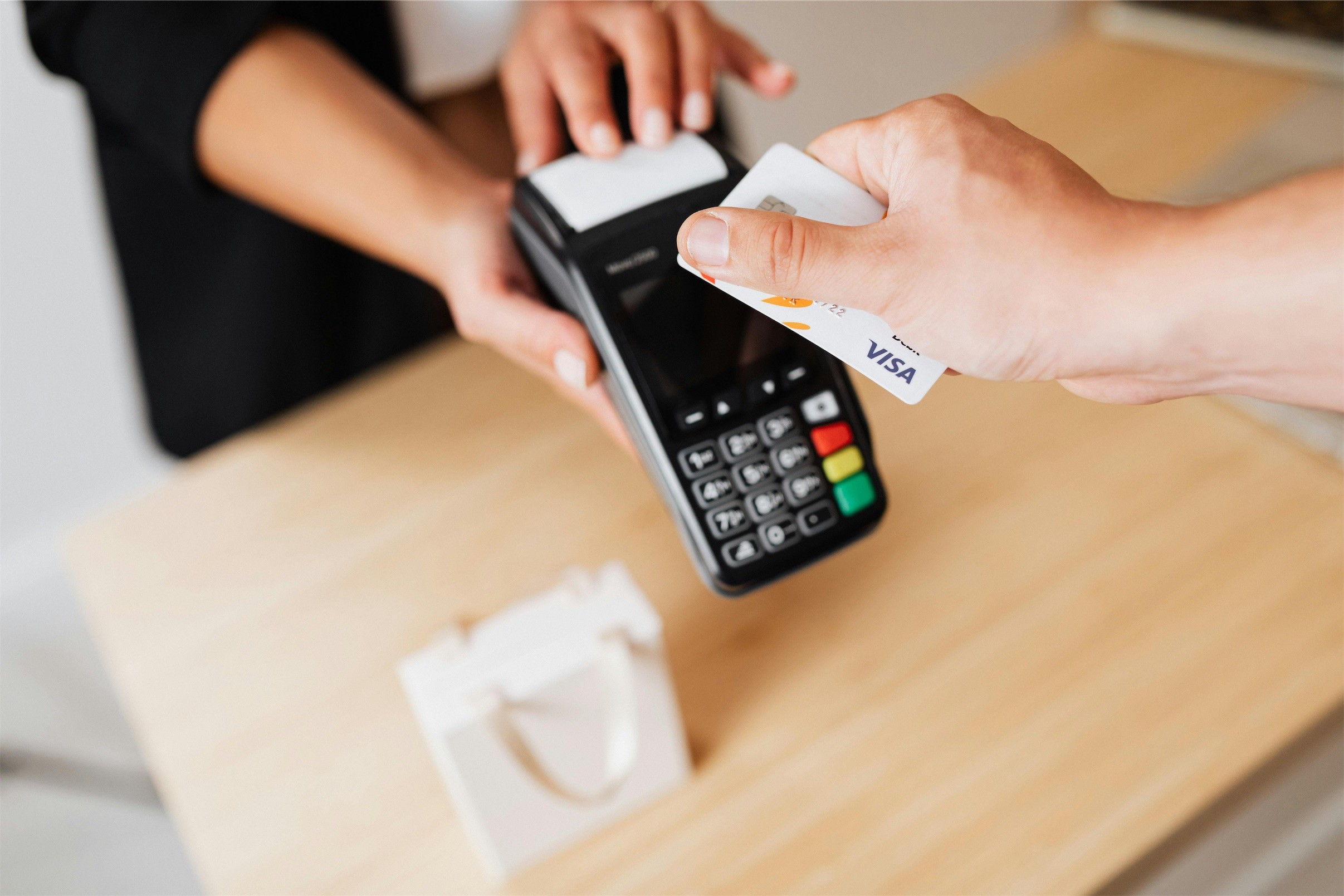 Un client règle par carte sur un terminal de paiement tenu au-dessus d'un comptoir.